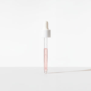 White dropper with a clear pink liquid on a white background