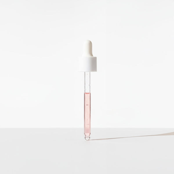 White dropper with a clear pink liquid on a white background